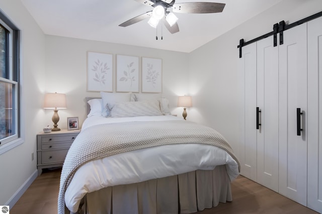 bedroom featuring hardwood / wood-style flooring, a barn door, and ceiling fan