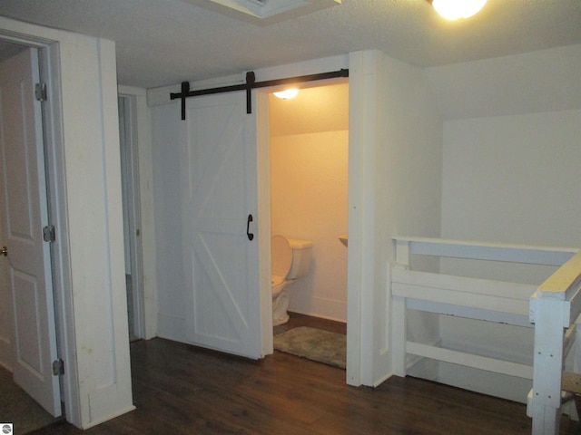 bedroom featuring ensuite bath, dark hardwood / wood-style floors, and a barn door