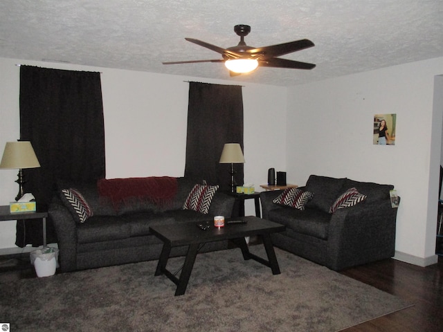 living room featuring ceiling fan, dark wood-type flooring, and a textured ceiling