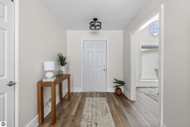 entryway featuring baseboards, a textured ceiling, and wood finished floors