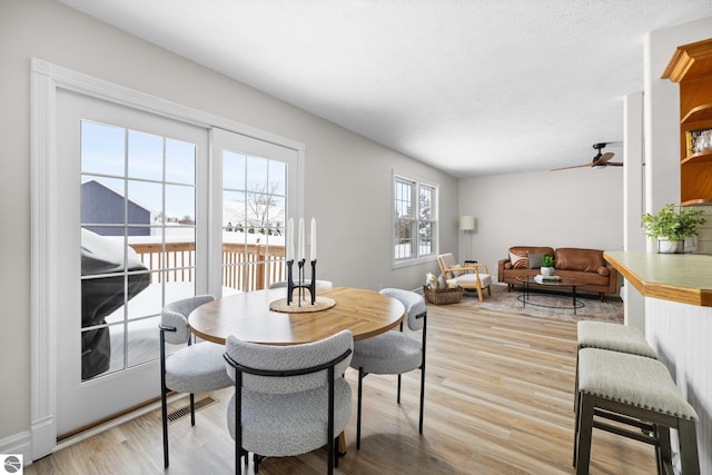 dining room with visible vents, baseboards, light wood-style flooring, and a ceiling fan