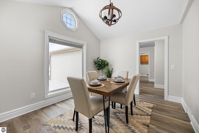 dining space with a chandelier, baseboards, wood finished floors, and vaulted ceiling