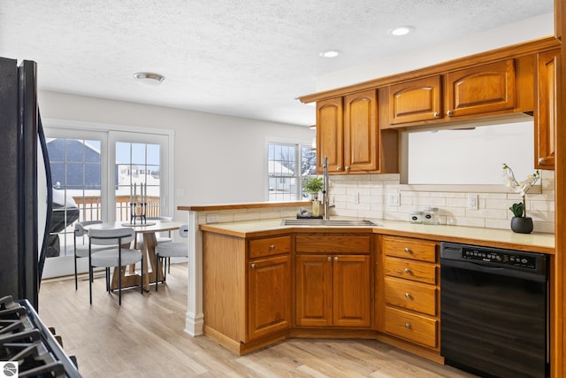 kitchen with dishwasher, light wood-type flooring, decorative backsplash, a peninsula, and refrigerator