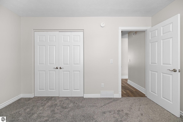 unfurnished bedroom featuring baseboards, visible vents, carpet floors, and a closet