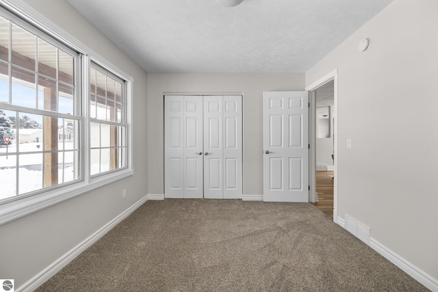 unfurnished bedroom with visible vents, baseboards, a closet, and carpet flooring