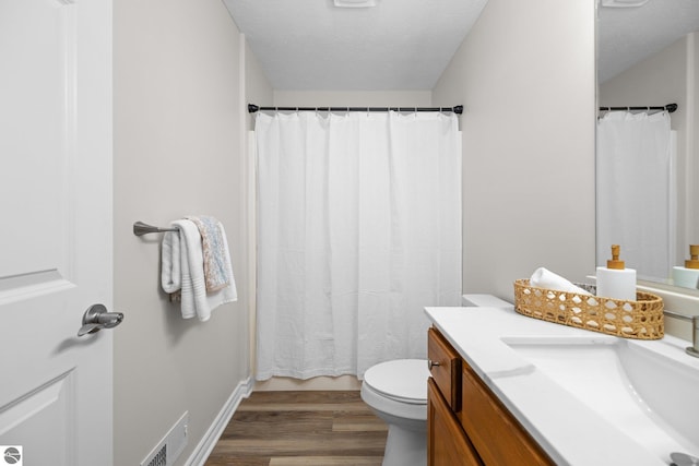 bathroom with vanity, wood finished floors, visible vents, a textured ceiling, and toilet