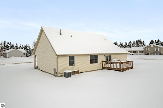 snow covered rear of property featuring a wooden deck and central AC unit