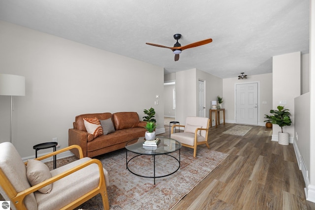 living room with ceiling fan, baseboards, a textured ceiling, and wood finished floors