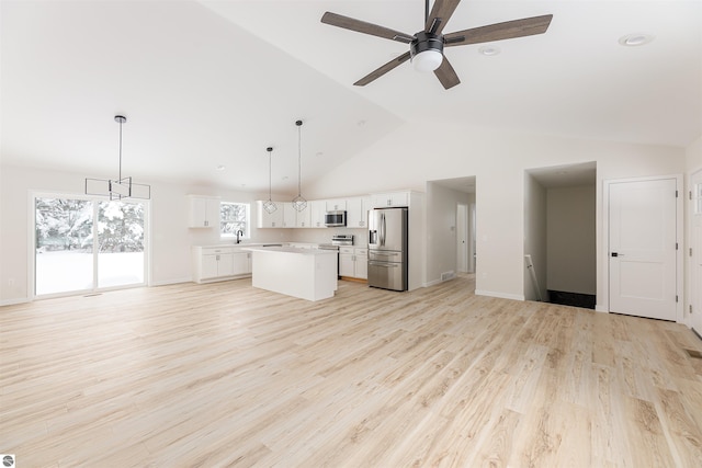 kitchen featuring appliances with stainless steel finishes, a center island, white cabinets, and decorative light fixtures