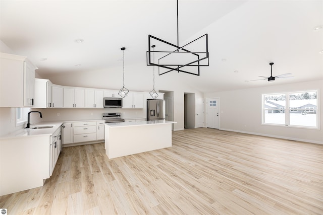 kitchen featuring sink, decorative light fixtures, a center island, stainless steel appliances, and white cabinets