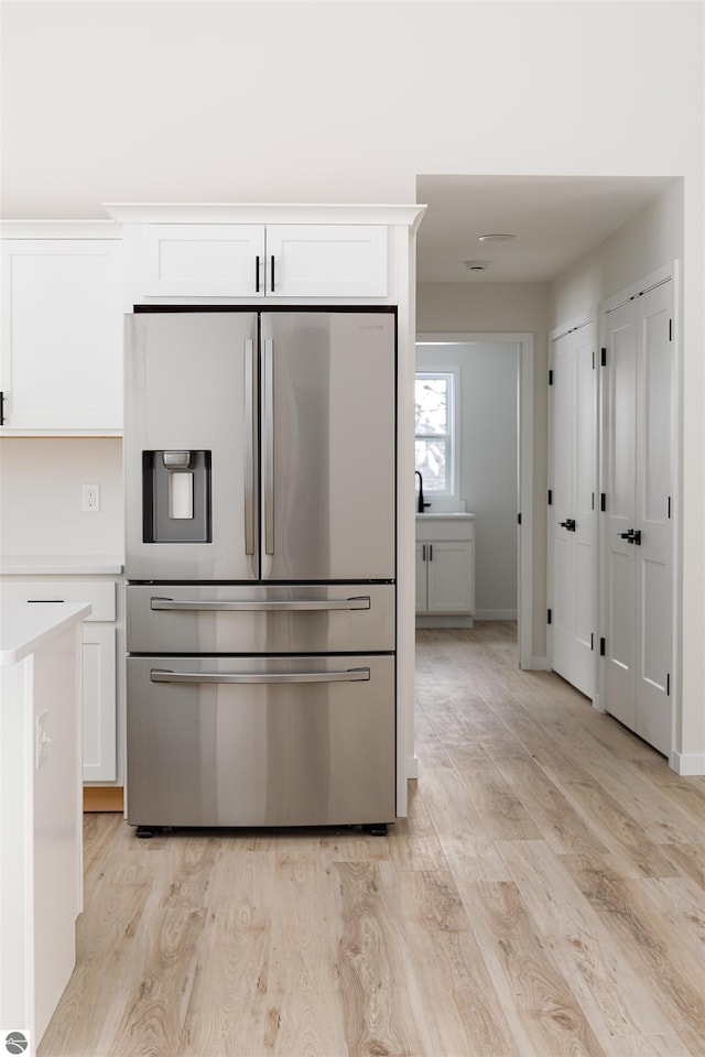 kitchen with white cabinetry, stainless steel fridge with ice dispenser, and light wood-type flooring