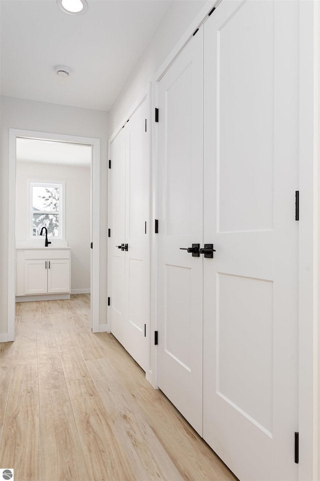 corridor with sink and light hardwood / wood-style flooring