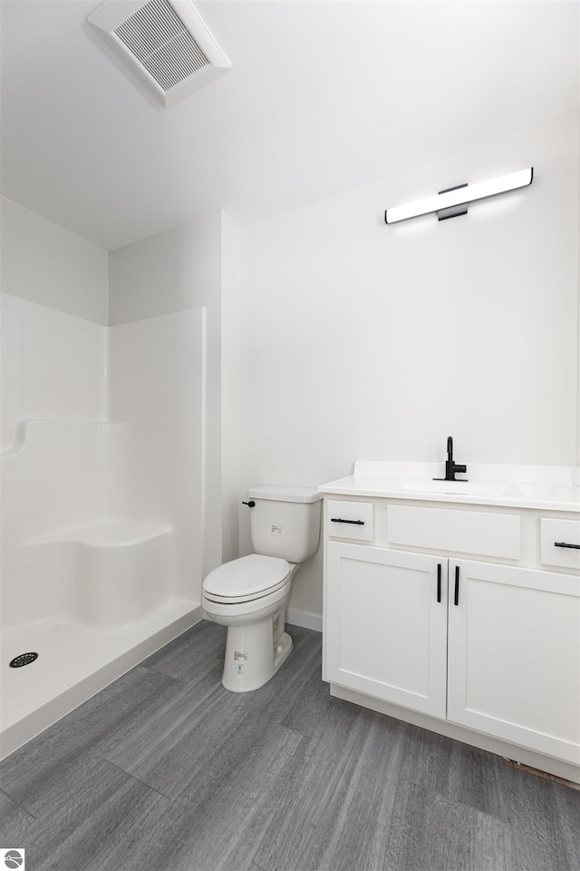 bathroom featuring vanity, a shower, hardwood / wood-style floors, and toilet