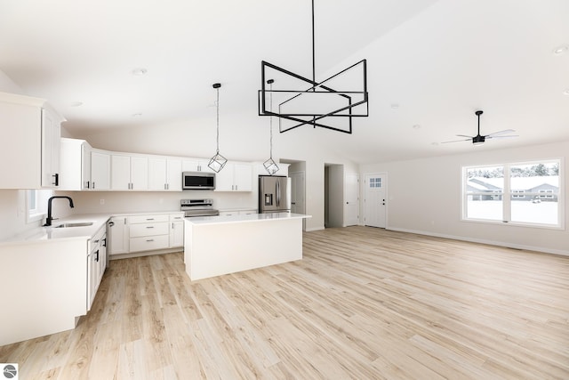 kitchen featuring pendant lighting, sink, appliances with stainless steel finishes, a center island, and white cabinets