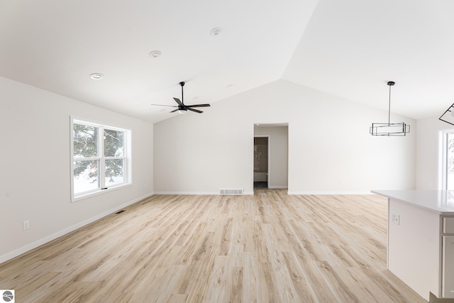 unfurnished living room featuring lofted ceiling, ceiling fan with notable chandelier, and light hardwood / wood-style flooring