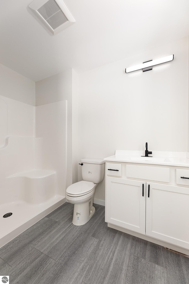 bathroom with vanity, hardwood / wood-style floors, toilet, and a shower