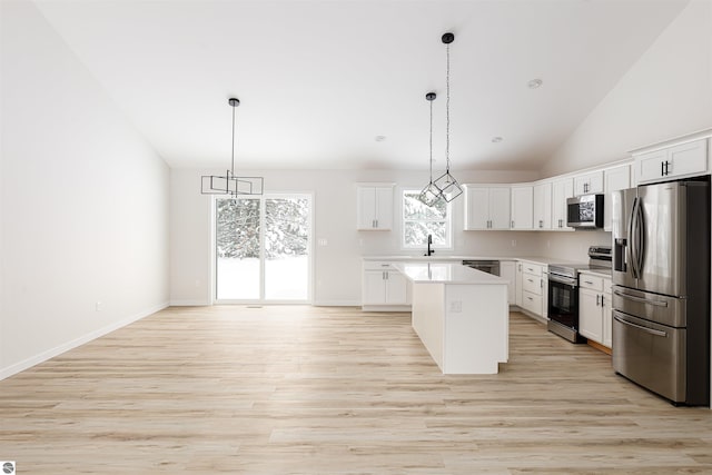 kitchen with light hardwood / wood-style flooring, white cabinetry, hanging light fixtures, stainless steel appliances, and a kitchen island