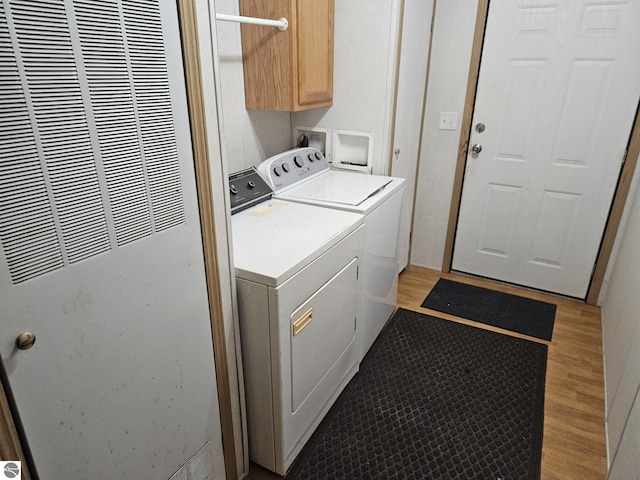 laundry area with cabinets, washing machine and clothes dryer, and light wood-type flooring