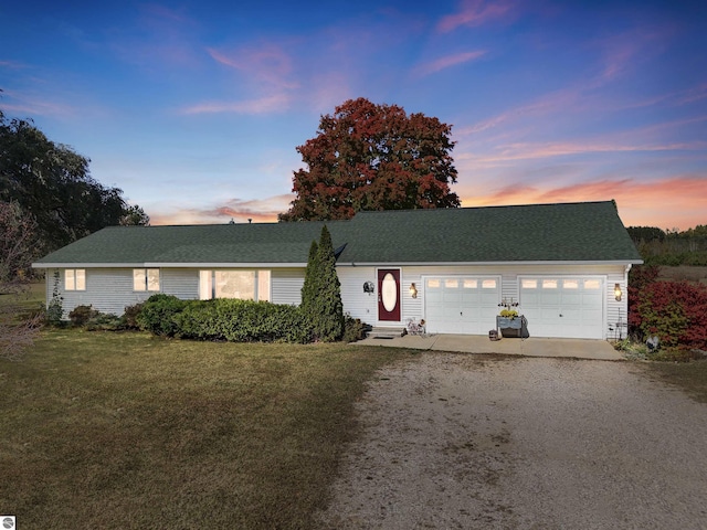 ranch-style home with a garage and a yard