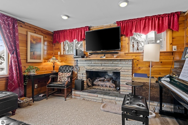 living room featuring a stone fireplace and wood walls