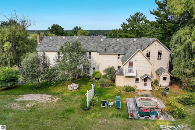 back of property with a yard and a balcony