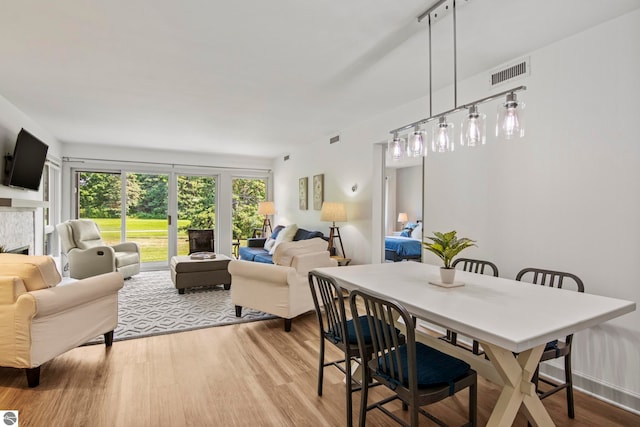 dining area featuring a tiled fireplace and light hardwood / wood-style flooring