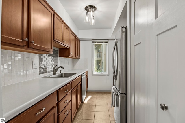 kitchen featuring appliances with stainless steel finishes, sink, light tile patterned floors, and backsplash