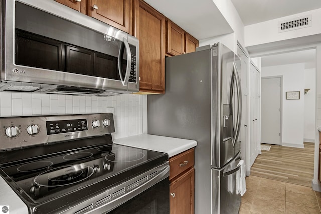 kitchen featuring light tile patterned floors, decorative backsplash, and appliances with stainless steel finishes