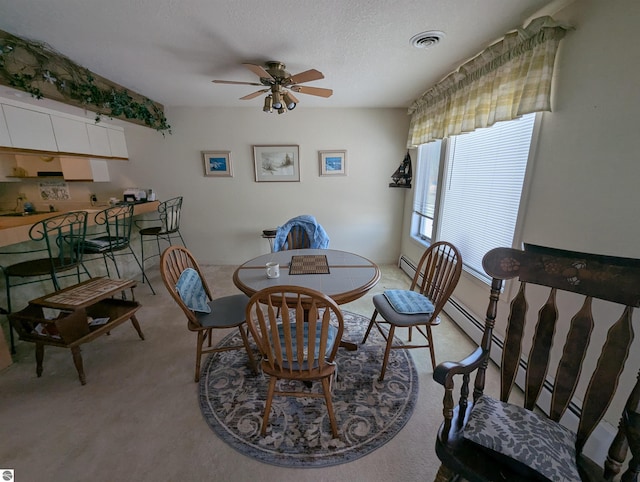 carpeted dining space with ceiling fan and a textured ceiling