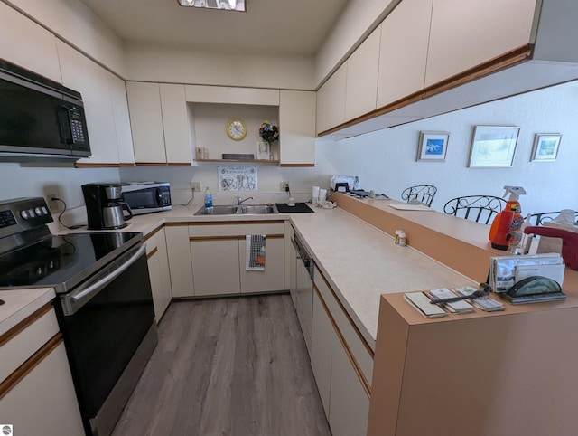 kitchen with white cabinetry, sink, light wood-type flooring, and appliances with stainless steel finishes