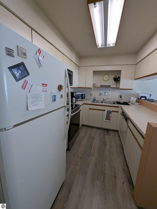 kitchen with sink, stainless steel appliances, light hardwood / wood-style floors, and white cabinets