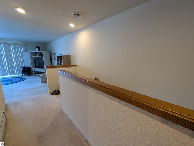 hall with a baseboard radiator and light colored carpet