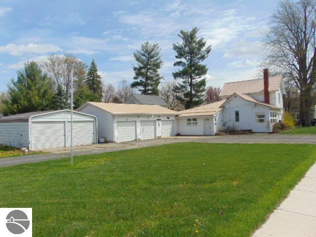 ranch-style house featuring an outbuilding, a chimney, and a front lawn
