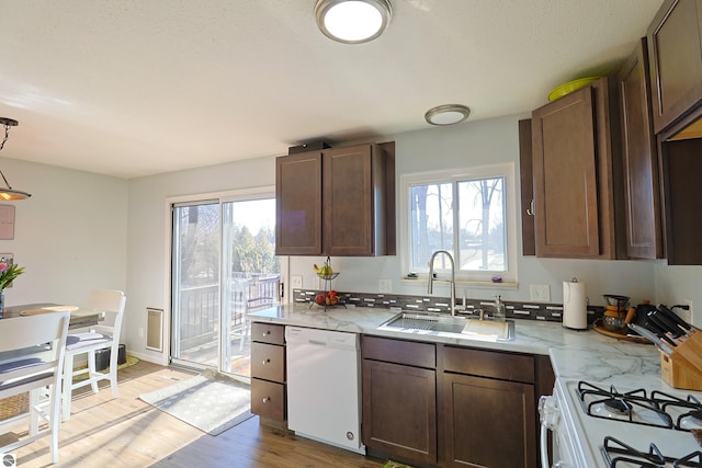 kitchen featuring sink, white appliances, hanging light fixtures, dark brown cabinets, and light hardwood / wood-style floors