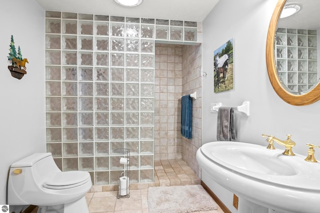 bathroom with tiled shower, tile patterned floors, toilet, and sink