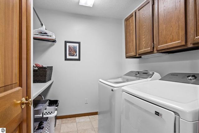 laundry area with cabinets, washing machine and dryer, and a textured ceiling