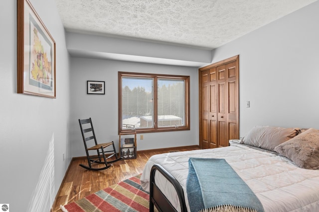 bedroom with hardwood / wood-style floors, a closet, and a textured ceiling