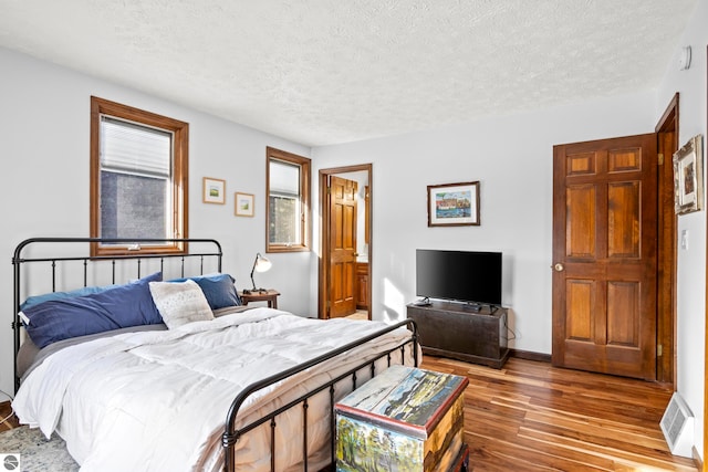 bedroom featuring hardwood / wood-style flooring and a textured ceiling