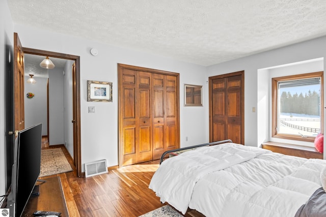 bedroom with a textured ceiling, access to exterior, dark hardwood / wood-style flooring, and a closet