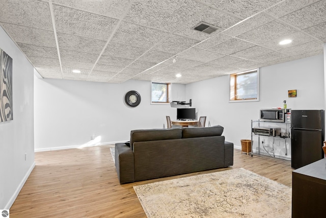 living room with a paneled ceiling and light wood-type flooring