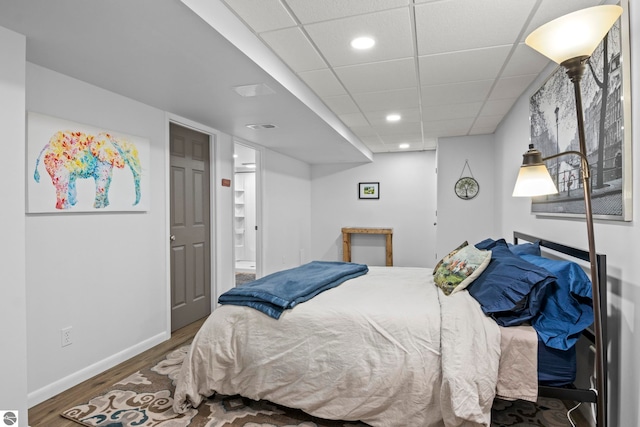 bedroom with a paneled ceiling and wood-type flooring