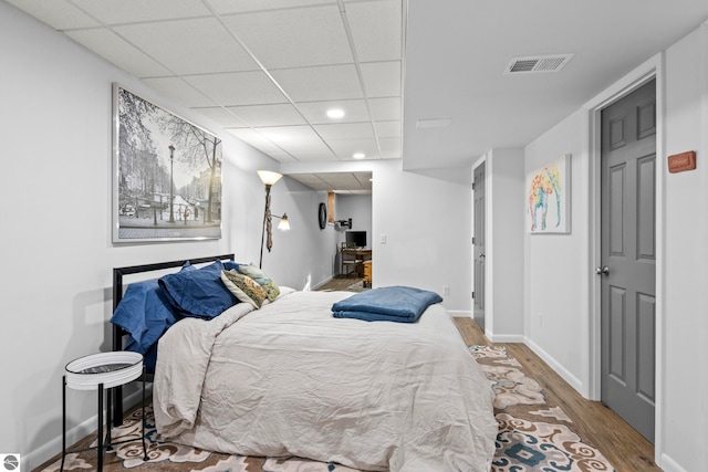 bedroom featuring hardwood / wood-style flooring and a drop ceiling