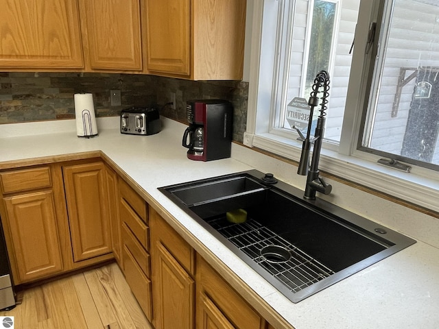 kitchen with tasteful backsplash, sink, and light hardwood / wood-style flooring