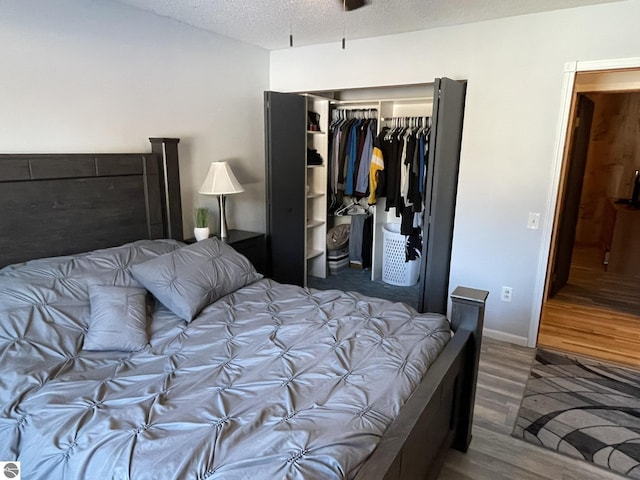 bedroom with dark hardwood / wood-style floors, a textured ceiling, and a closet