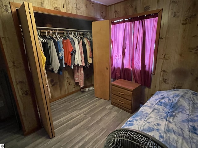 bedroom with wood-type flooring, a closet, and wood walls