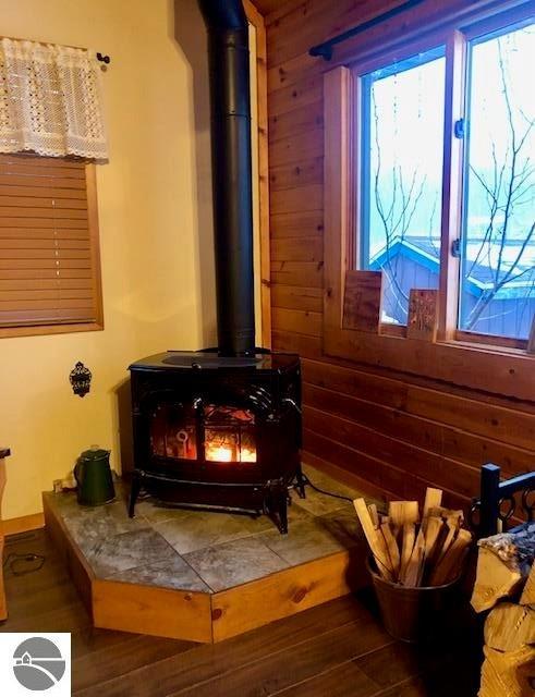 room details with a wood stove, hardwood / wood-style floors, and wood walls