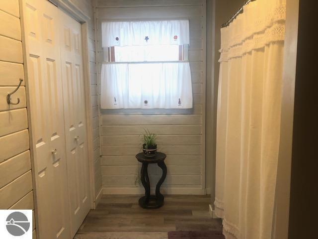 doorway to outside featuring hardwood / wood-style flooring and wooden walls