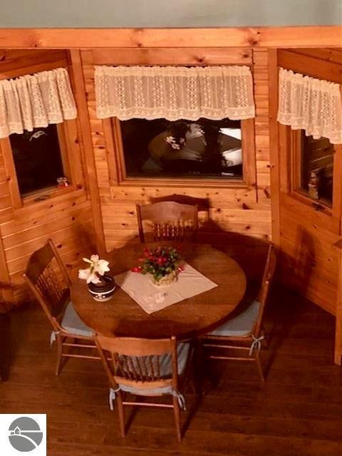 dining space with dark hardwood / wood-style flooring and wood walls