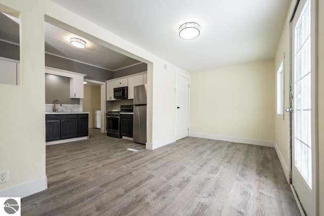 kitchen with sink, stainless steel appliances, white cabinets, and light wood-type flooring