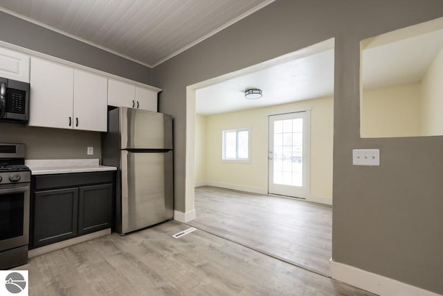 kitchen with white cabinetry, ornamental molding, appliances with stainless steel finishes, and light hardwood / wood-style floors